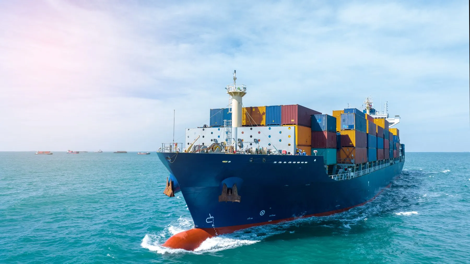 A container ship heading towards the camera through blue water