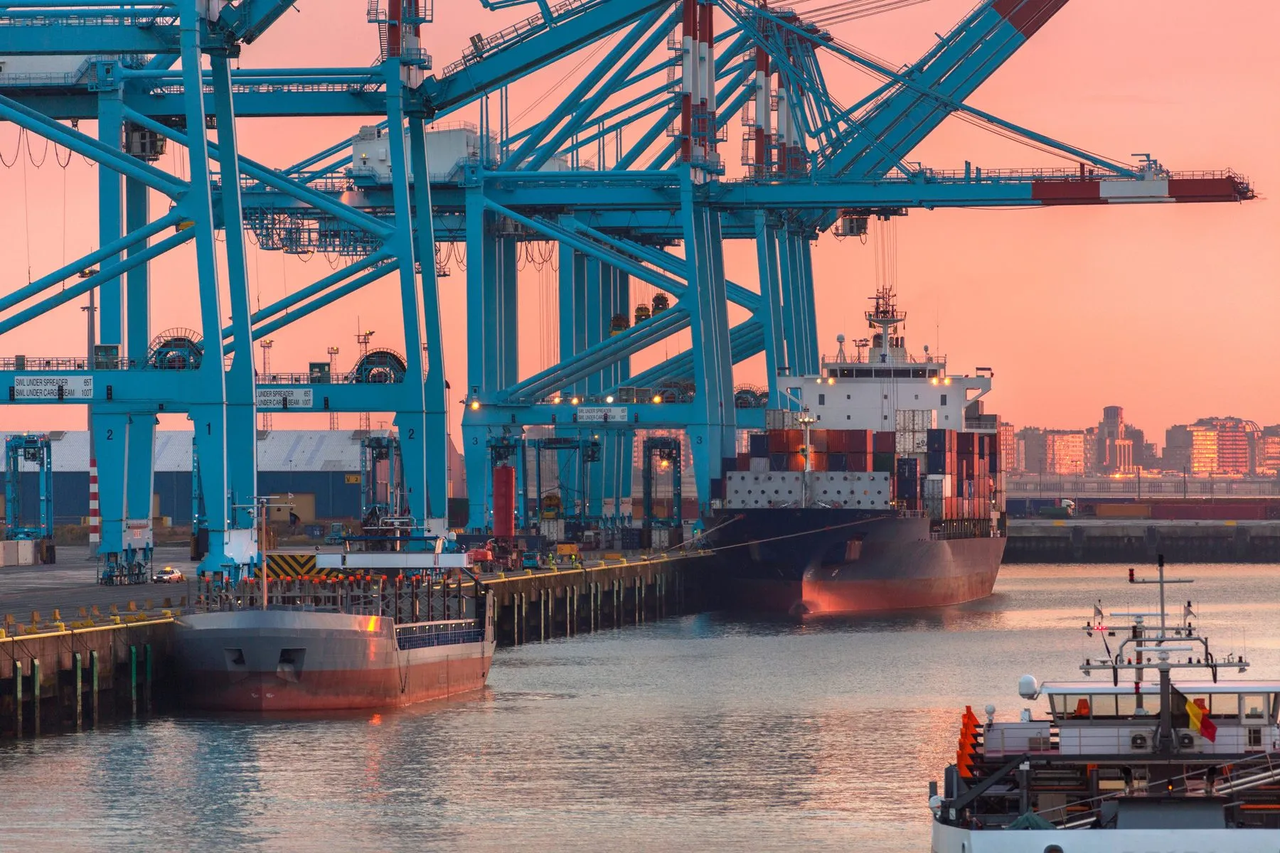 Container cranes and a ship at the Port of Zeebrugge at sunset